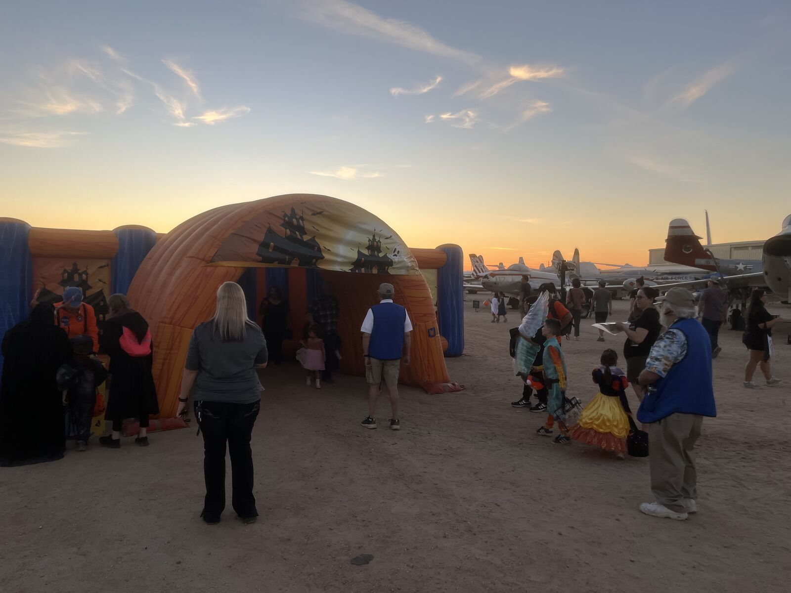 Families in costume at a Halloween inflatable tunnel at sunset